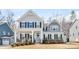 Charming two-story home features a covered porch, well-manicured lawn, and stylish architectural details at 14130 Sunnyhill Grove Rd, Davidson, NC 28036