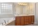 Bathroom with double sink vanity, framed mirror, natural light, soaking tub, and wood cabinets at 142 Mills Ln, Fort Mill, SC 29708