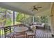 Inviting screened porch featuring a comfortable seating area and a ceiling fan overlooking the wooded backyard at 142 Mills Ln, Fort Mill, SC 29708