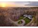 Aerial view of a beautifully landscaped property surrounded by mature trees with a sunrise backdrop at 1426 Merrimont Ave, Kings Mountain, NC 28086