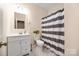 Clean bathroom featuring a striped shower curtain, white vanity, and a tile floor at 1513 Fletcher Broome Rd, Monroe, NC 28112