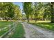 Long gravel driveway lined by split rail fence and mature trees leading to property at 1513 Fletcher Broome Rd, Monroe, NC 28112