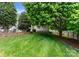 Picturesque backyard with lush grass, brick retaining wall, and shade trees at 196 Gabriel Dr, Mooresville, NC 28115