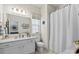 Bright bathroom with a white vanity, large mirror, and bathtub with shower curtain at 2147 Stevens Mill Rd, Matthews, NC 28104