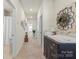 Hallway with neutral walls and carpet, leading to various rooms with decoratively framed artwork and furniture at 2147 Stevens Mill Rd, Matthews, NC 28104