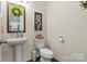 Charming powder room with pedestal sink, toilet, and decorative artwork on the wall at 2147 Stevens Mill Rd, Matthews, NC 28104