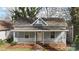 Charming one-story home featuring a covered front porch with white railings and mature trees at 314 Flint St, Charlotte, NC 28216