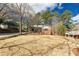 Quaint brick home with light-colored siding is set on a grassy lawn with mature trees and blue skies at 428 Chester St, Lancaster, SC 29720
