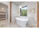 Bright bathroom with a stand-alone tub, marble floors, and a view from the window at 5124 Lansing Dr, Charlotte, NC 28270