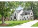 Beautiful white brick home with manicured lawn, mature trees, and modern gray accents on windows at 5124 Lansing Dr, Charlotte, NC 28270