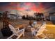 Backyard patio featuring stone fire pit with Adirondack chairs, and professionally landscaped yard at dusk at 5367 Heartwood Ln, Denver, NC 28037