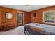 Cozy bedroom featuring wood-paneled walls, a window, a trunk, and an external door at 5912 Potter S Rd, Waxhaw, NC 28173