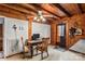 Living area featuring wood paneling, ceiling beams, desk area, and an outside-access door at 5912 Potter S Rd, Waxhaw, NC 28173