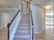 Entry way staircase features carpet steps, white spindles, and stained wood railing at 8414 Bampton Dr, Concord, NC 28027