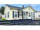 View of charming yellow home showcasing the enclosed front porch and stylish black shutters at 101 Loya St, Mount Holly, NC 28120