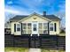Charming yellow home featuring a cozy front porch and a stylish black fence at 101 Loya St, Mount Holly, NC 28120