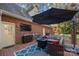Inviting brick patio with a cozy seating area, fire pit, outdoor TV, and shaded umbrella at 102 Wyndham Way, Salisbury, NC 28147