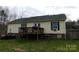 View of backyard with wood deck and outdoor seating, a green lawn and a wooded perimeter at 14440 W Highway 55 Hwy, Blacksburg, SC 29702