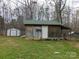 View of the outbuilding with a white door, green roof, and additional lean-to style shelter at 14440 W Highway 55 Hwy, Blacksburg, SC 29702