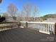 Spacious deck with wooden railings overlooking a serene lake, bordered by mature trees and clear skies at 2339 Perry Rd, Denver, NC 28037