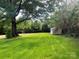 A lush green backyard with a storage shed surrounded by mature trees at 317 Kings Mountain St, York, SC 29745