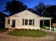 Charming cottage-style home with a manicured lawn, gravel driveway, and a dark green metal roof at 317 Kings Mountain St, York, SC 29745