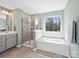 Well-lit bathroom featuring a separate shower and tub, gray cabinets, and dual sinks at 3441 Scottish Fern Ln, Indian Land, SC 29707