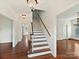 Bright foyer with hardwood floors, a staircase with white risers, and elegant lighting fixtures at 7811 Biddstone Ct, Charlotte, NC 28226