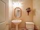 Charming powder room featuring a pedestal sink, decorative mirror, and a toilet, maximizing space efficiency at 805 Stack Rd, Monroe, NC 28112