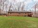View of the backyard with a red brick house, a lush lawn, and a wooden fence at 9524 Fairlane Dr, Charlotte, NC 28214