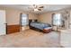 Carpeted bedroom with a ceiling fan, two windows with curtains, dresser, and bed at 9524 Fairlane Dr, Charlotte, NC 28214