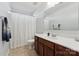 Well-lit bathroom with a wood vanity, white sink, and shower with a white curtain at 1102 Less Traveled Trl, Indian Trail, NC 28079