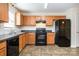 Bright kitchen featuring tile floors, wood cabinets, black appliances, and lots of light at 128 Locomotive Ln # 110, Mooresville, NC 28115