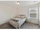 Cozy bedroom with a patterned bedspread, bedside table, and natural light from the window at 15954 Harbor Hill Dr, Charlotte, NC 28273