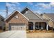 Beautiful brick home featuring a cozy front porch with seating, complemented by a well-maintained lawn at 1715 Rhynes Trl, Rock Hill, SC 29732