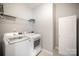 Well-lit laundry room with a washer and dryer and wire shelving for storage, next to a white door at 1715 Rhynes Trl, Rock Hill, SC 29732