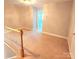 Carpeted hallway with wooden banister and a view of a brightly lit room at 18845 Cloverstone Cir, Cornelius, NC 28031