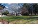 A green backyard with mature trees surrounding it and building structures behind it at 2530 31St Street Ne Dr, Hickory, NC 28601