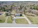 Aerial shot displays a quaint home with gravel driveway, surrounded by lush greenery and mature trees, offering privacy at 4450 Flowes Store Rd, Concord, NC 28025