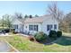 Charming white home features green shutters, front porch seating, and well-maintained landscaping for an inviting curb appeal at 4450 Flowes Store Rd, Concord, NC 28025