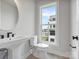 Stylish half bathroom with pedestal sink, toilet, round mirror and a window with city view at 5003 Tiny Ln, Charlotte, NC 28203