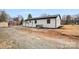 A view of the backyard with a white brick home, gravel, and a shed at 6301 Vernedale Rd, Charlotte, NC 28212