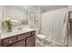 Well-lit bathroom with a shower featuring a decorative shower curtain, vanity with decor, and framed art at 8573 River Ridge Dr, Charlotte, NC 28213