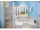 Modern bathroom boasts a glass shower, garden tub, and window overlooking a green space, creating a spa-like retreat at 9200 Four Acre Ct, Charlotte, NC 28210