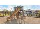 Community playground with green and tan play structures and a mulch ground covering, with a clubhouse visible in the background at 9534 Maltese Dr, Gastonia, NC 28056