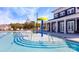 Community swimming pool with a splash pad, a dark clubhouse with large windows and lounge chairs around the pool deck at 9534 Maltese Dr, Gastonia, NC 28056