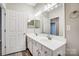 Bathroom with dual sinks, large mirror, wood-look flooring, and white cabinets at 10011 Forest View Ln, Charlotte, NC 28213