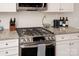 Close-up of stainless steel stove with oven, granite countertop, white subway tile backsplash, and white cabinets at 1915 Colony Line Ct, Charlotte, NC 28210