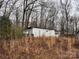 Exterior view of a white metal building, surrounded by bare trees and overgrown weeds at 2211 Unionville Indian Trl, Indian Trail, NC 28079