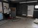 View inside the garage, including its peeling paint, shelving, and metal garage door at 2211 Unionville Indian Trl, Indian Trail, NC 28079